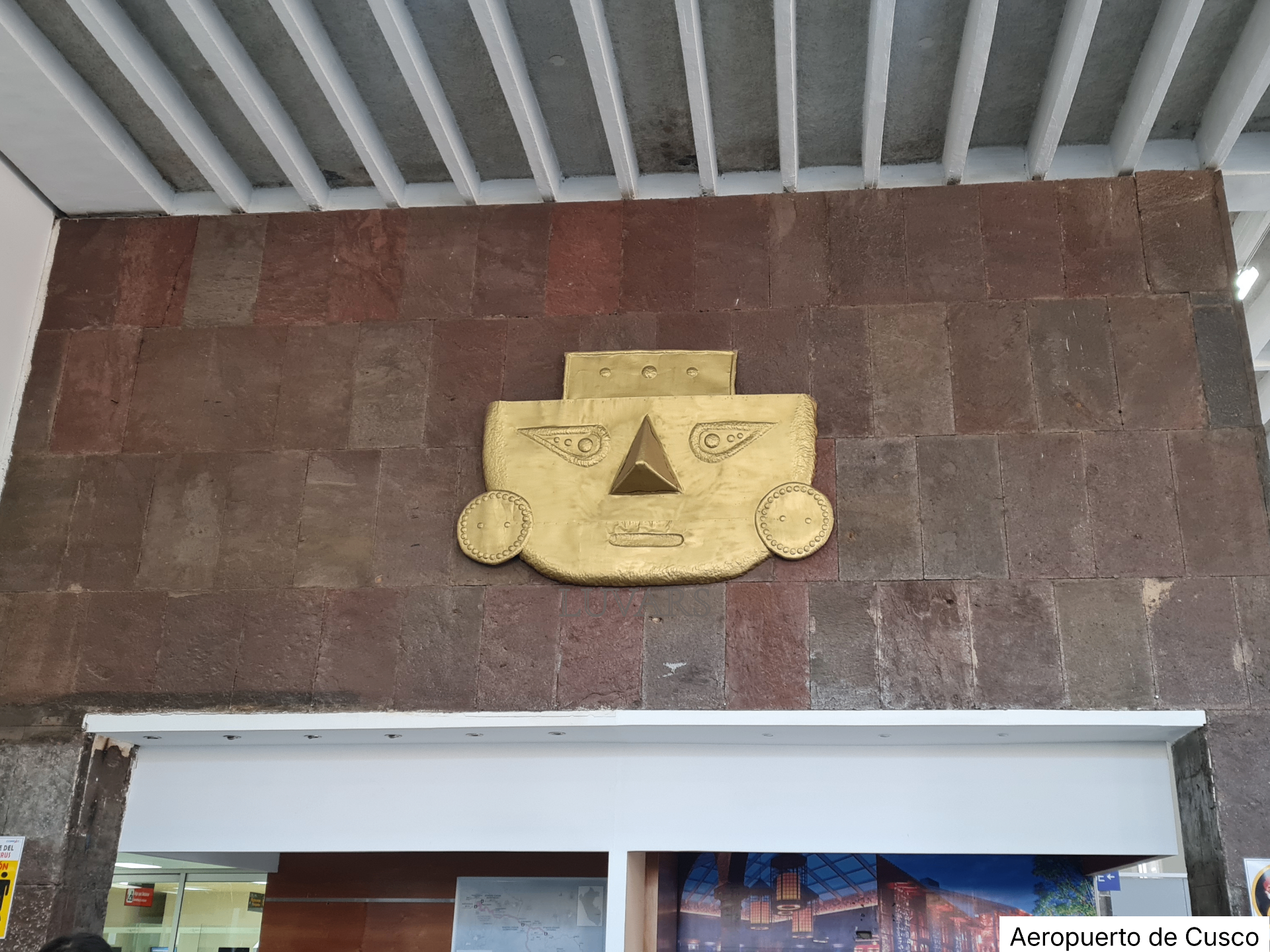 Máscara dorada inca sobre muro de piedra en el Aeropuerto de Cusco