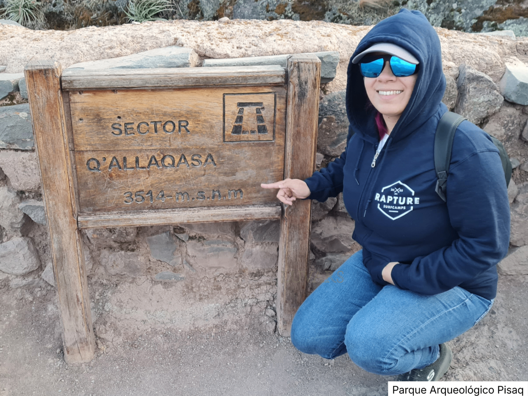 Persona sonriente señalando el letrero del Sector Q'Allaqasa en el Parque Arqueológico Pisaq a 3514 m.s.n.m.